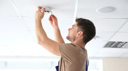 A technician checking workplace smoke detector