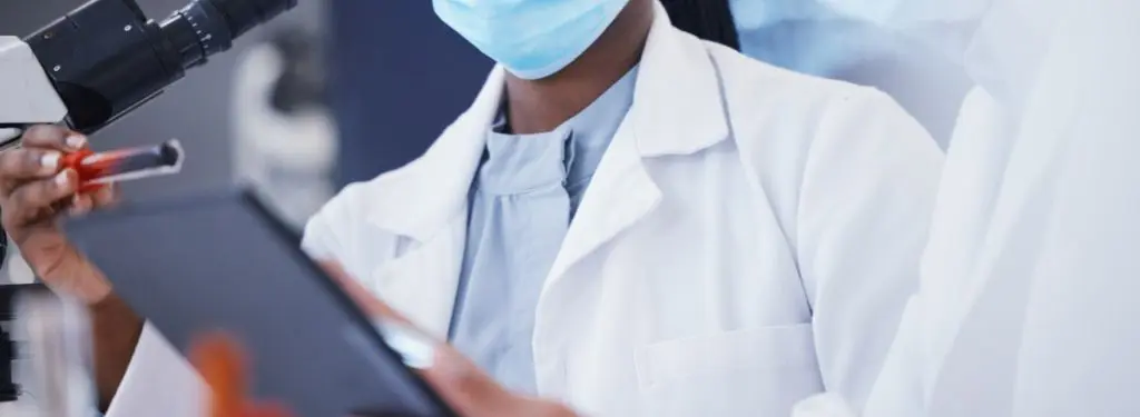 lab workers using a vaccine management software on a tablet while testing out chemicals