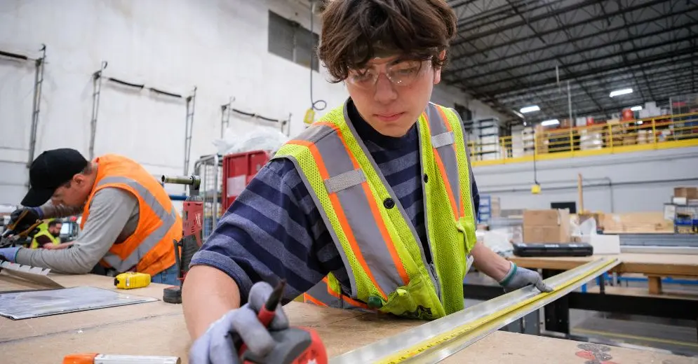 worker helping measure wood as part of the product development process