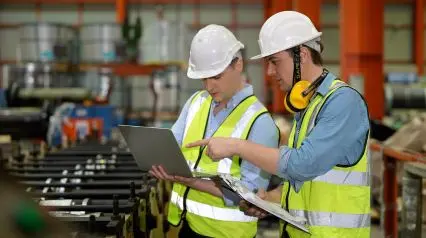 two quality engineers talking about potential process failures using a PFMEA template on a laptop