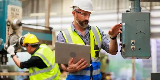 electrical worker following operator safety guidelines on their laptop while in a control room