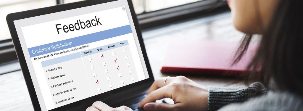 a product quality manager reviewing customer feedback using enterprise feedback management software on laptop